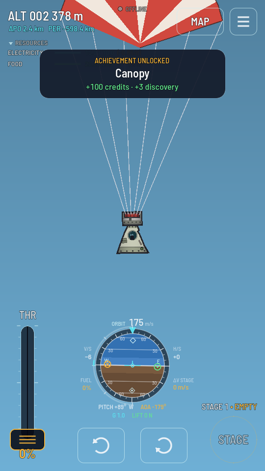 The rocket hanging under an open parachute over the ground.